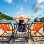 005521600_1688358365-woman-with-hat-sitting-chairs-beach-beautiful-tropical-beach-woman-relaxing-tropical-beach-koh-nangyuan-island